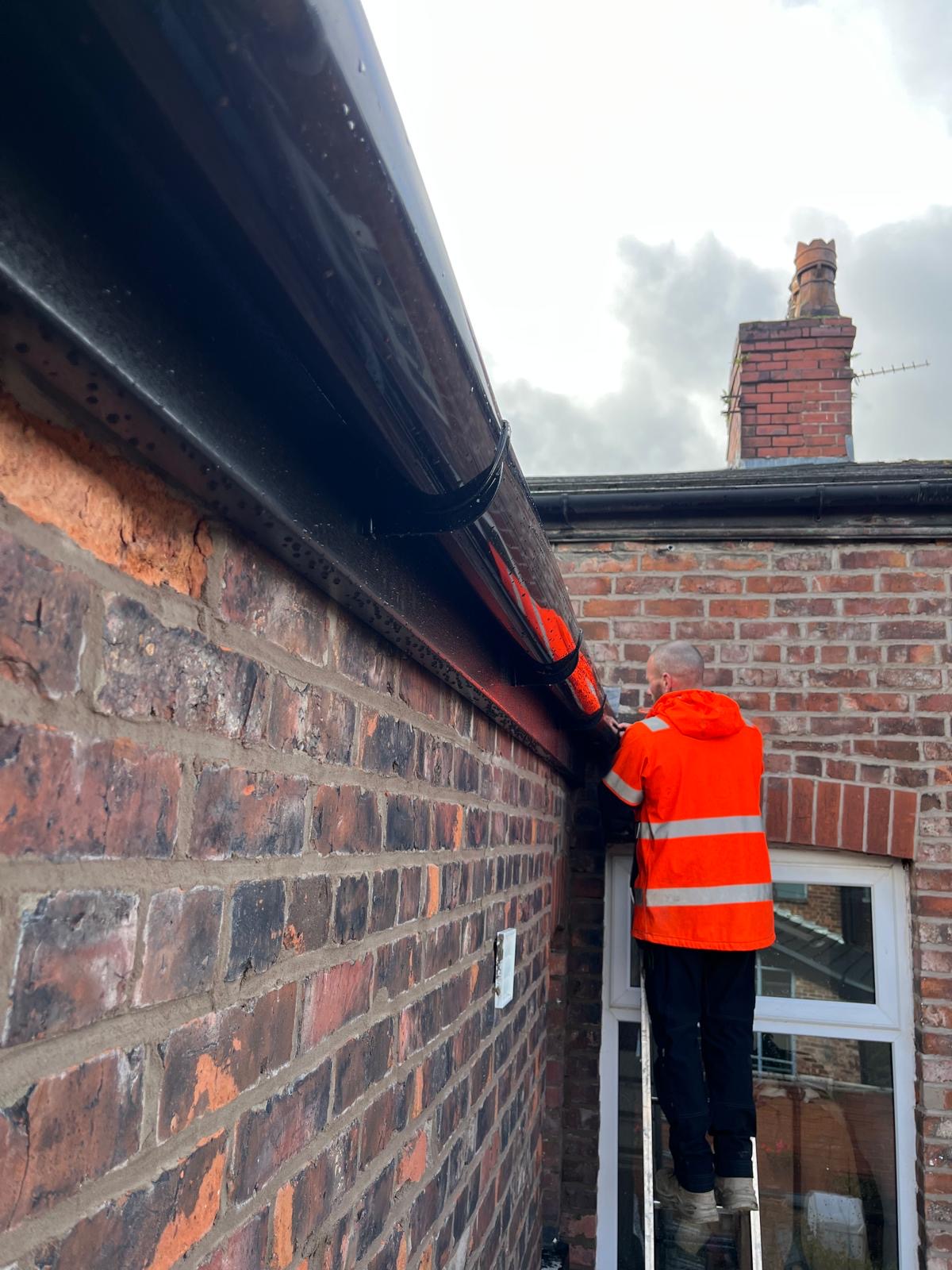 Fitting new black guttering on a brick home